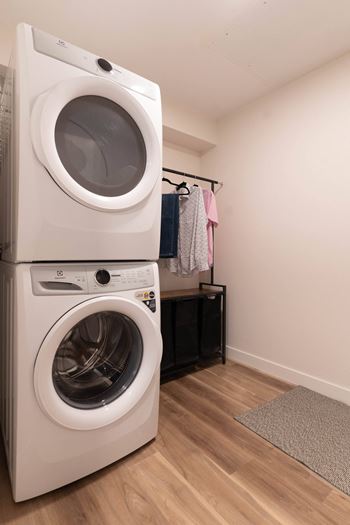 A white front loading washing machine is stacked on top of another one in a laundry room.
