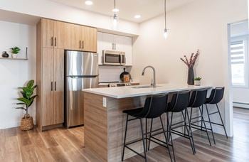 A kitchen with a refrigerator, microwave, and sink.