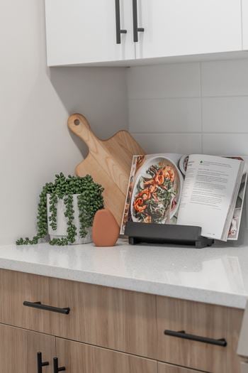 A cutting board, a knife, and a magazine are on a kitchen counter.