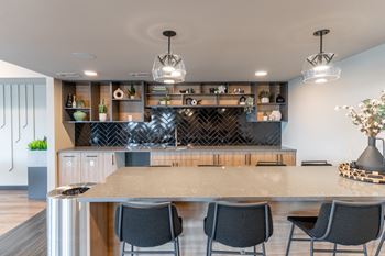 A modern kitchen with a bar area and black chairs.