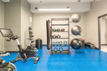A gym room with a blue floor and a variety of exercise equipment.