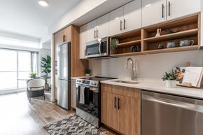 Calgary apartment for rent - A modern kitchen with wooden cabinets and stainless steel appliances.at Podium Apartments, Calgary, AB