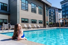 Calgary apartment for rent - A Woman In a Blue Bikini Sits By a Pool at Podium Apartments, Alberta, T2E 7J2
