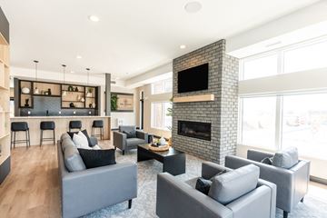 Calgary townhouse for rent - A modern living room with grey couches and a fireplace.