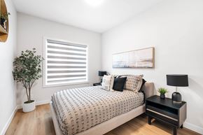 Winnipeg apartment for rent - A bedroom with a bed, nightstand, and a plant.