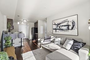 Regina apartment for rent - A modern living room with a grey couch and a large abstract painting on the wall.