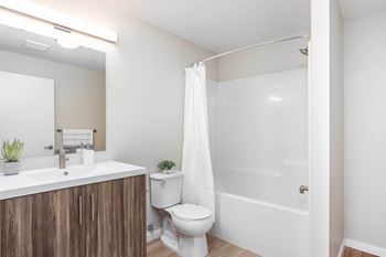 A white bathroom with a toilet, sink, and shower.