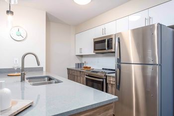 A kitchen with a stainless steel refrigerator, microwave, and sink.