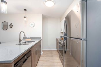 A kitchen with a sink, refrigerator, and cabinets.