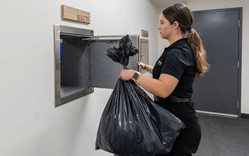 A woman is carrying a black trash bag