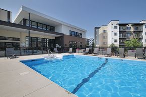 Winnipeg apartment for rent - A large swimming pool in front of a building with apartment complexes in the background.