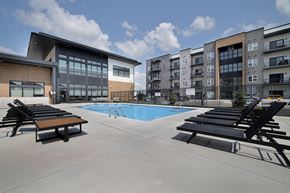 Winnipeg apartment for rent - A swimming pool area with sun loungers and a building in the background.