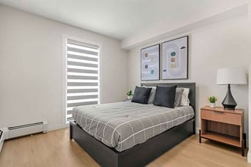 Calgary apartment for rent - A bedroom with a large bed and a wooden nightstand.