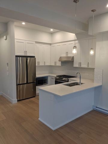 Delta apartment for rent - A kitchen with a stainless steel refrigerator and white cabinets.