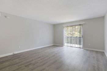 A room with wooden flooring and a window with blinds.