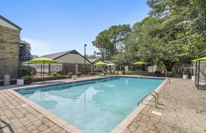Hoover apartment for rent - A large outdoor swimming pool surrounded by a brick patio and trees at The Onyx Hoover Apartments, Hoover, 35216