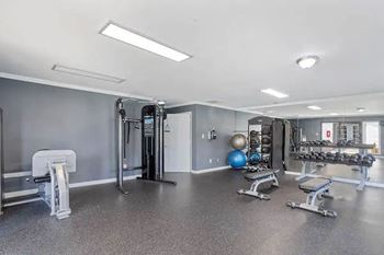 A spacious gym with a variety of equipment including a treadmill, weights, and a bench press.