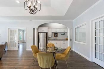 A dining room with a glass table and yellow chairs.