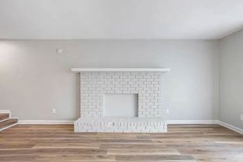 A white brick fireplace in a room with wooden floors.
