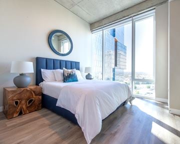 Nashville apartment for rent - A bedroom with a large bed and a view of the city.
