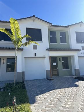 Fort Myers apartment for rent - A white house with a green door and a palm tree in front.