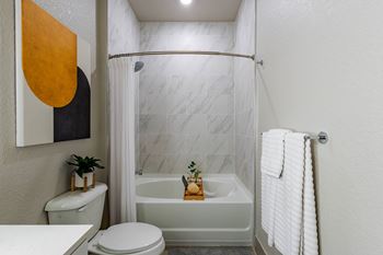 A bathroom with a white toilet, a white bathtub, and a white shower curtain.