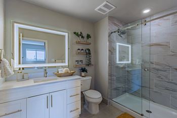 A bathroom with a marble tile shower and a white toilet.
