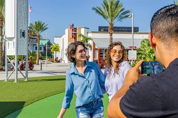 Two women are walking and taking a picture of themselves with a man.