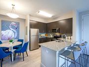 Fort Myers apartment for rent - a kitchen with a large island with granite countertops and dark wood cabinets at The Orchard at Portofino Vineyards, Fort Myers