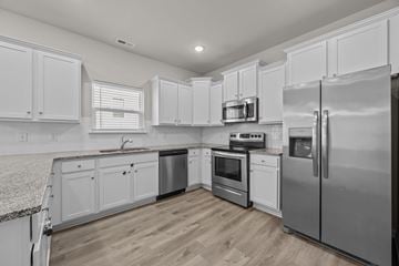 Charlotte apartment for rent - A modern kitchen with white cabinets and stainless steel appliances.
