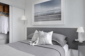 Toronto apartment for rent - A bedroom with a large bed, a nightstand with a lamp, and a picture hanging above the bed.
