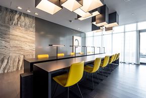 Toronto apartment for rent - A modern dining room with yellow chairs and a marble wall.