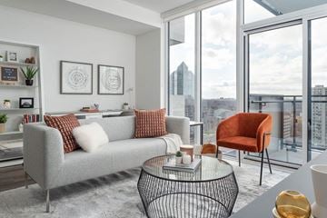Toronto apartment for rent - A grey couch with red pillows sits in a modern living room with a view of the city.