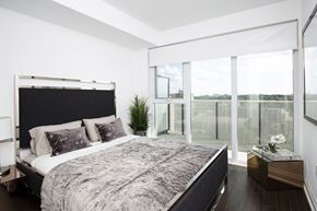 York apartment for rent - A bedroom with a large bed and a view of the outside through the window.