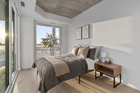 Ottawa apartment for rent - A bedroom with a large bed and a small table by the window.