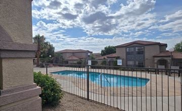 Sierra Vista apartment for rent - A pool surrounded by a black fence with a house in the background.