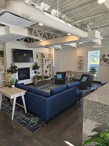South Salt Lake apartment for rent - A living room with a blue couch and a television on the wall.