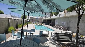 South Salt Lake apartment for rent - A pool area with a table and chairs under a shade umbrella.