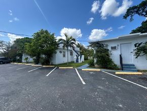 Miami apartment for rent - A white building with a palm tree in front of it.