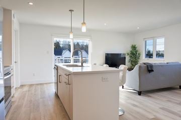 Dieppe apartment for rent - A modern kitchen with a white island and a grey couch in the living room.