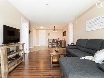Dieppe apartment for rent - A living room with a grey couch and a wooden entertainment center.