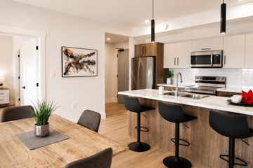 Dieppe apartment for rent - A modern kitchen with a wooden table and black bar stools.