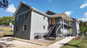 Birmingham apartment for rent - A grey building with a yellow door and a staircase leading to the second floor.