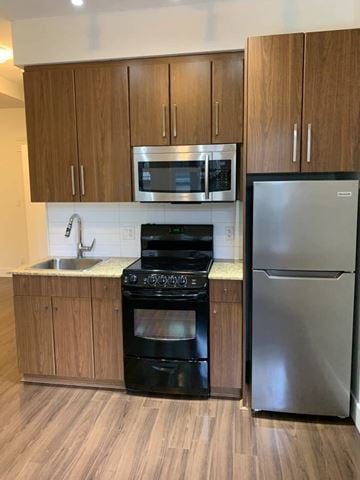 Vancouver apartment for rent - A kitchen with a stainless steel refrigerator and black oven.