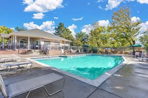 Arvada apartment for rent - bright blue pool with lawn chairs surrounding the outside and an outside deck overlooking the pool with two bbqs