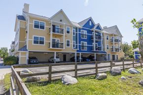 Denver apartment for rent - A large apartment building with multiple balconies and a parking area in front.