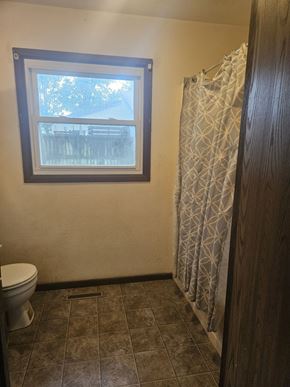 Newton apartment for rent - A bathroom with a toilet, a window and a shower curtain.