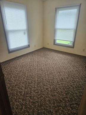 Newton apartment for rent - A room with a carpeted floor and two windows.