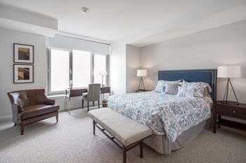 A bedroom with a bed and a chair and a window