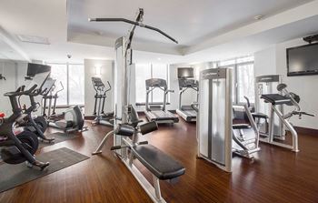A gym with various exercise machines and a tv